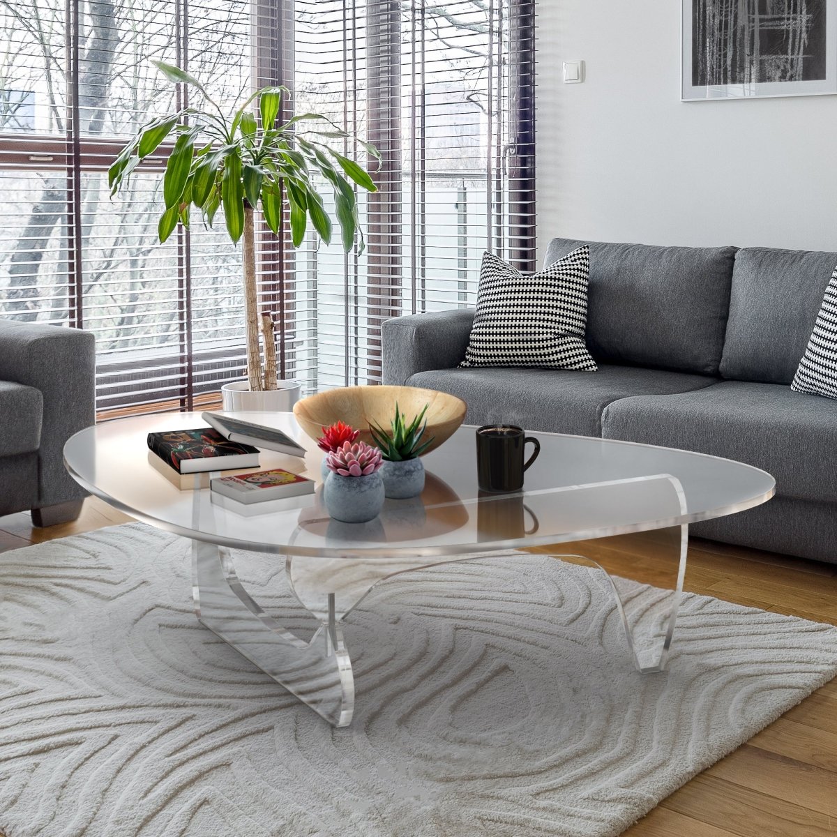 Noguchi style clear acrylic table in a livingroom with a white carpet and light wood flooring.