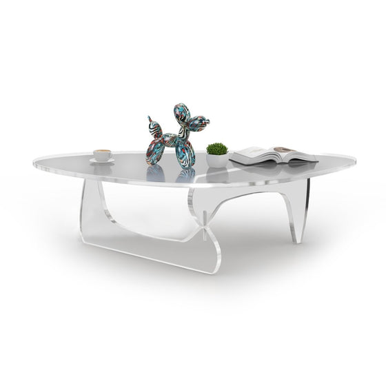 Noguchi clear acrylic table  with a ballon dog and a a book on top in a white background.
